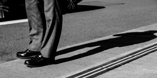 Low section of businessman standing on sidewalk in city