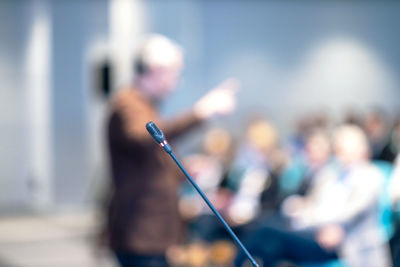 Microphone in focus, blurred speaker and audience at workshop, business conference or presentation