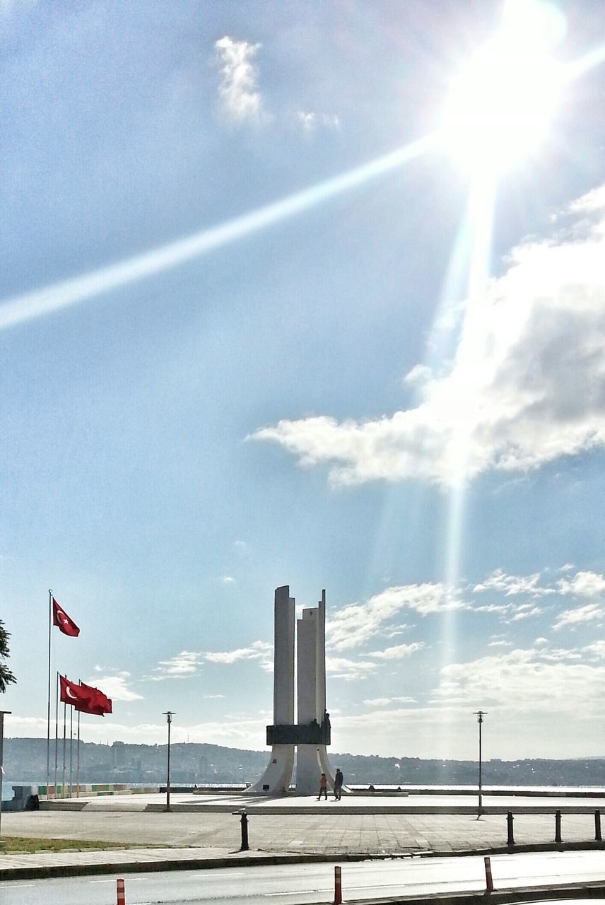 sun, sky, sunlight, sea, sunbeam, flag, horizon over water, cloud - sky, sunny, transportation, cloud, lens flare, scenics, nature, beauty in nature, day, beach, national flag, outdoors, tranquility