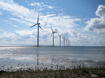 Windmills on sea against sky