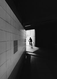 Silhouette man walking on footpath in tunnel
