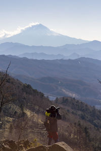 Rear view of woman photographing mountains