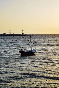 Silhouette boat sailing on sea against clear sky during sunset