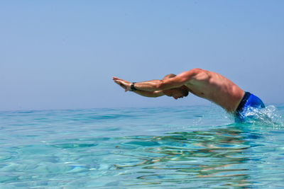 Side view of shirtless man diving in sea