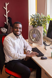 Smiling young businessman using computer at desk in office