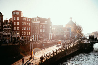 Canal passing through city buildings against clear sky