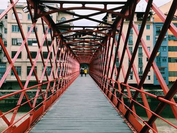 Rear view of friends walking on footbridge in city