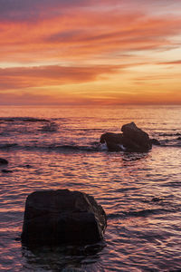 Rocks on sea against sky during sunset