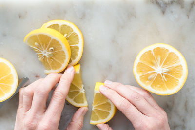 Cropped image of hand holding lemon on table