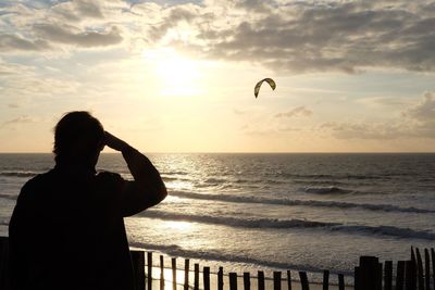 Silhouette person standing against sea during sunset