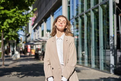 Portrait of young woman standing in city