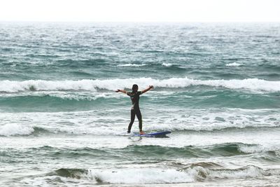 Man jumping on beach against sky