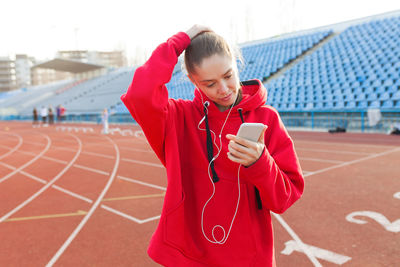 Woman using mobile phone while standing on running track