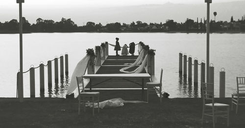 Women standing on jetty over river on wedding day