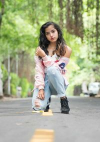 Portrait of young woman kneeling on road