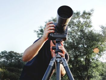 Low angle view of man photographing against sky