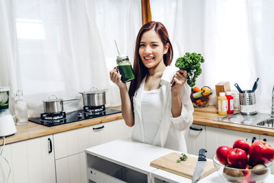 Portrait of young woman holding juice at home