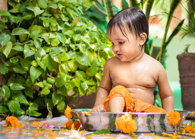 Cute toddler baby boy bathing in decorated bathtub at outdoor from unique perspective