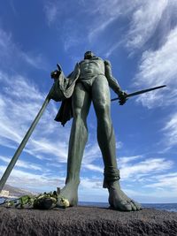 Low angle view of statue on field against sky