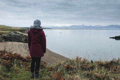 Rear view of woman standing on water against sky