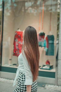 Side view of woman standing on footpath by store window