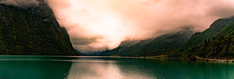 Scenic view of lake by mountains against sky