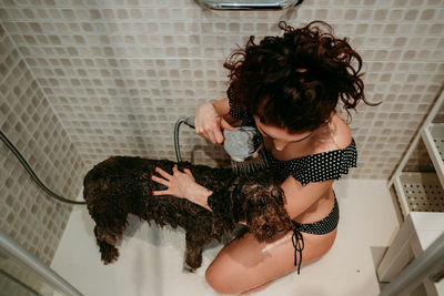 High angle view of woman bathing dog in bathroom