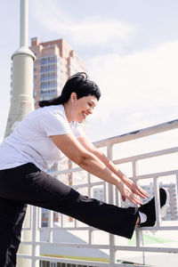 Side view of woman standing against railing in city