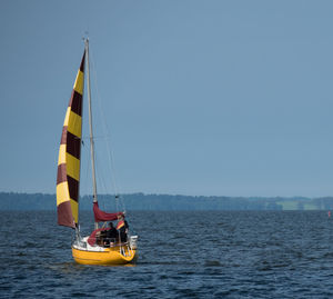 Sailboat sailing on sea against clear sky