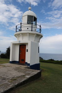 Lighthouse by sea against sky