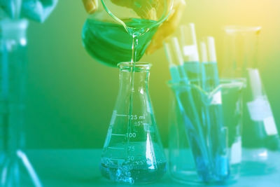 Cropped image of hand pouring chemical in container at laboratory