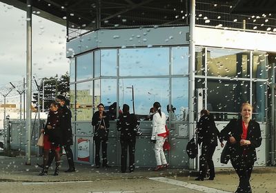 People standing by window against sky
