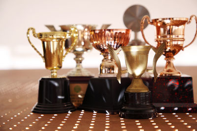 Close-up of trophies on table against wall