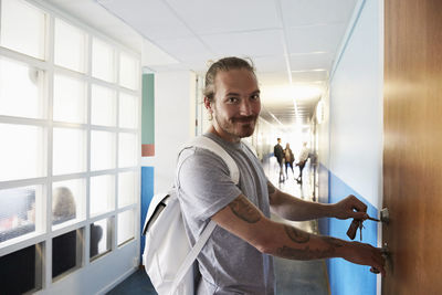 Side view portrait of young man standing against window