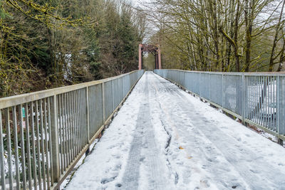 Snow covered footbridge against sky