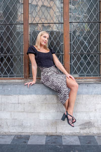 Portrait of young woman standing against wall