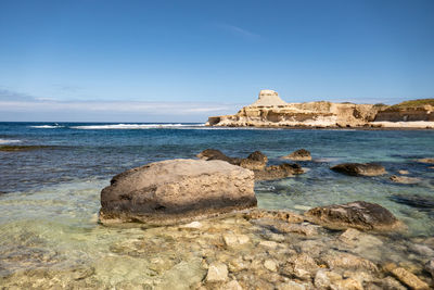 Rock formation on beach against sky