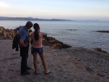 Rear view of man and woman standing on promenade against sky