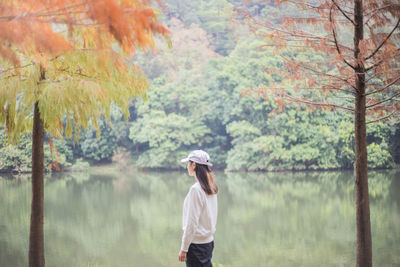 Rear view of person standing by trees in forest during autumn