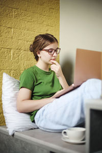 Young woman looking away while sitting on floor