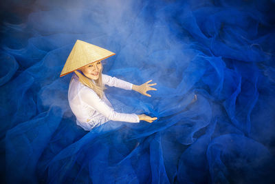 Portrait of smiling woman sitting on blue fishing net