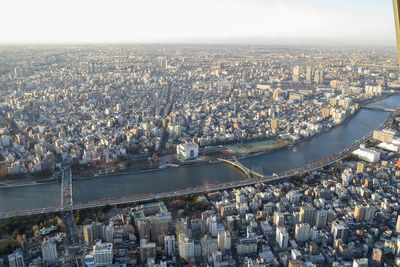 Aerial view of city by river and buildings against sky