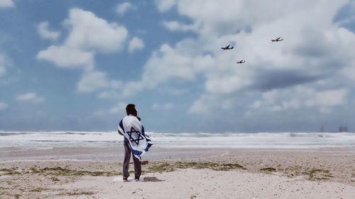 Rear view of man standing on sea shore