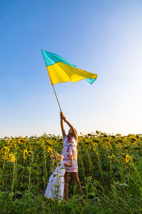 Rear view of woman holding umbrella against sky