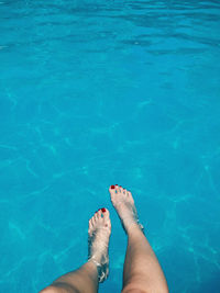 Low section of woman legs in blue swimming pool