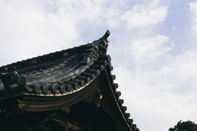 Low angle view of roof of building against cloudy sky