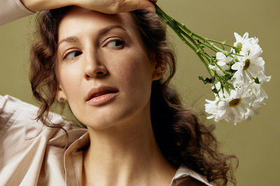 Close-up of young woman looking away while holding flowers