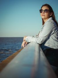 Portrait of woman wearing sunglasses on beach against clear sky