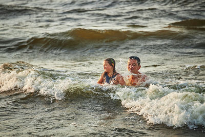 Little girl and her dad playing with waves in the sea. family summer vacations. family play in sea