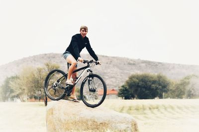 Full length of man riding bicycle against sky